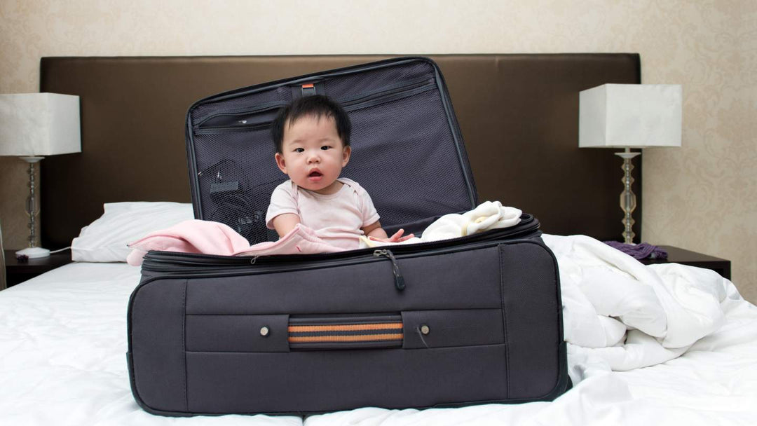 child sitting in suitcase on bed